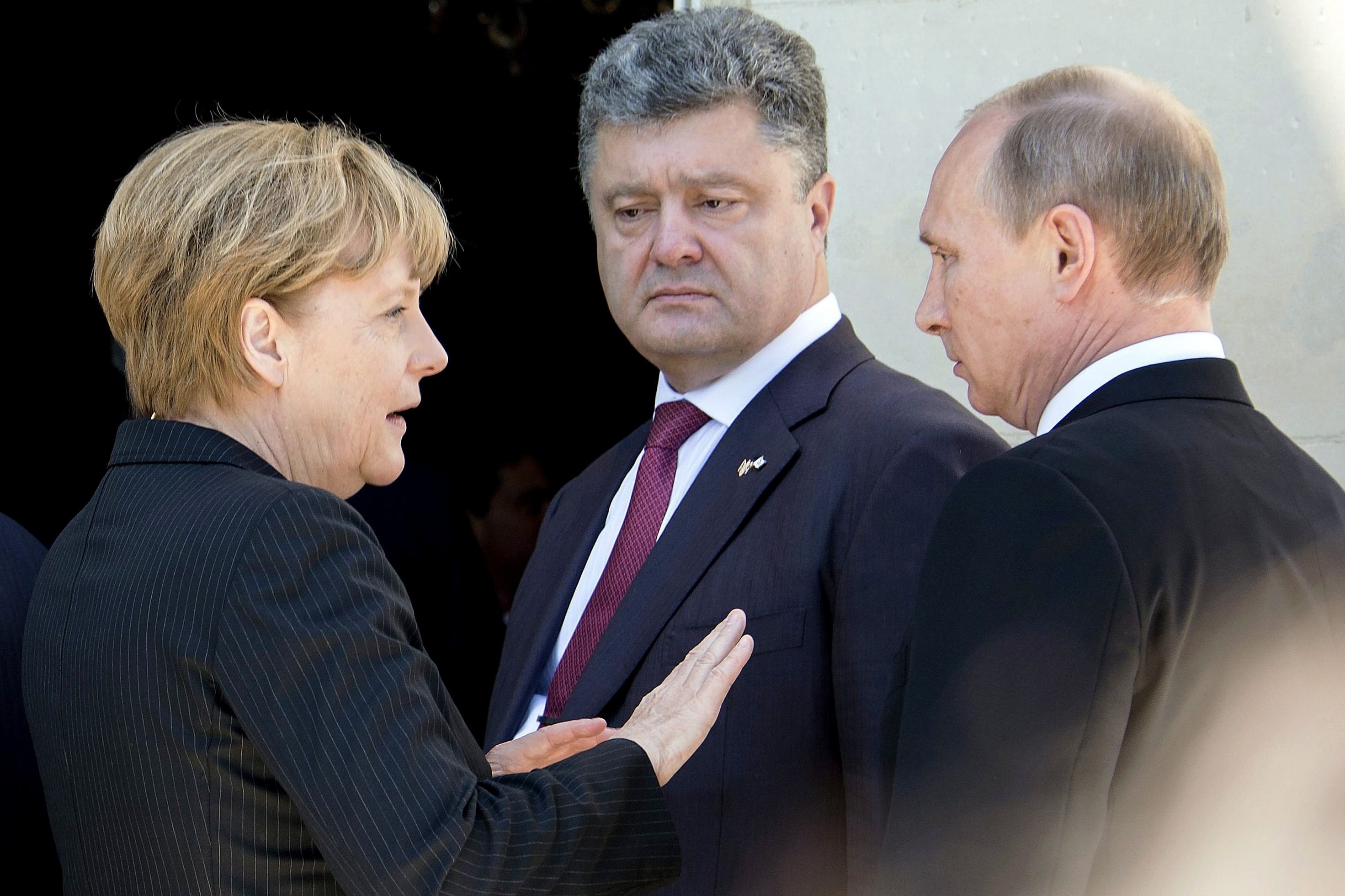 epa04242302 A handout photo providede by the German government (Bundesregierung) press service on 06 June 2014 of German Chancellor Angela Merkel (L), Ukrainian president-elect Petro Poroshenko (C) and Russia's president Vladimir Putin (R) as they meet for an official meal on occasion of the 70th anniversary of the Allied tropps' landing in the Normandy, in front of the castle of Benouville in Ouistreham, France, 06 June 2014. EPA/Guido Bergmann/BUNDESREGIERUNG/HANDOUT
