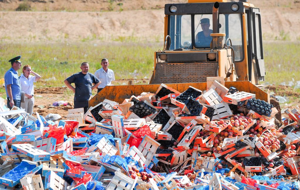 A worker uses a bulldozer to crush crates of peaches outside the city of Novozybkov, about 600 km from Moscow, on August 7, 2015. Russian officials on August 6 steamrollered tonnes of cheese as they began a  controversial drive to destroy Western food smuggled into the crisis-hit country despite a public outcry. President Vladimir Putin last week signed a decree ordering the trashing of all food -- from gourmet cheeses to fruit and vegetables -- that breaches a year-old embargo on Western imports imposed in retaliation to sanctions over the Ukraine crisis. AFP PHOTO / ONLINER.BY        (Photo credit should read -/AFP/Getty Images)